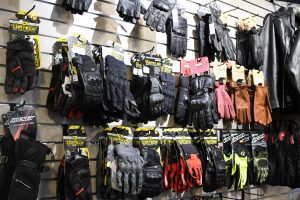 Motorcycle gloves in several colors hang on a wall display at Hattiesburg Cycles.