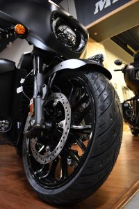 A close-up shows the front tire and brake of a black motorcycle on display at Hattiesburg Cycles.