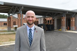 Petal Elementary School Principal Luke Daniels stands outside a school building under construction.