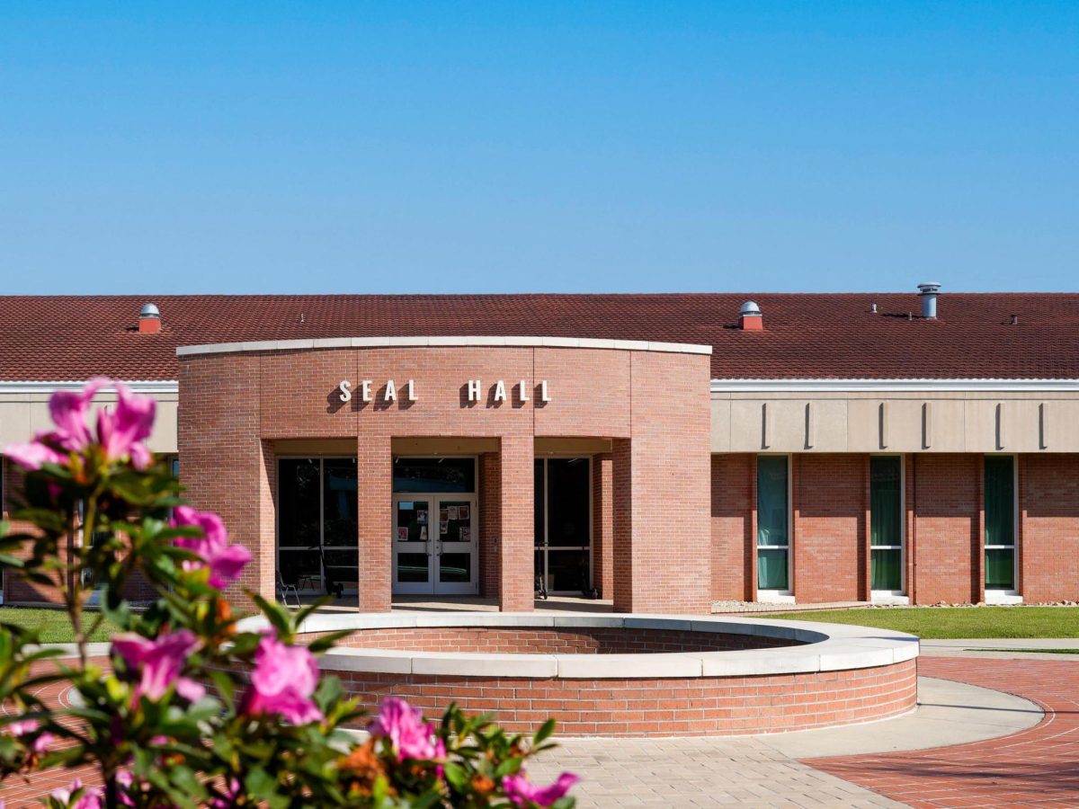 A brick building with white letters spelling “Seal Hall” above the entrance.