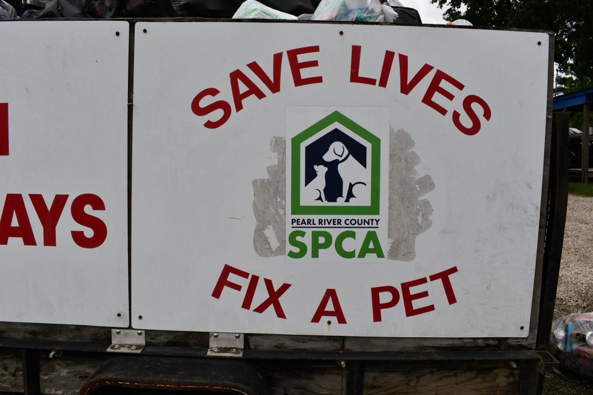 A white sign with the Pearl River County SPCA logo reads, “Save Lives Fix a Pet.”