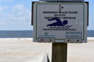 A sign on the beach informs visitors that water quality is tested regularly.