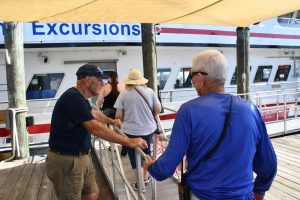 A tour guide leads a group of visitors toward a Ship Island Excursions boat.