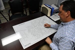 A man seated at a conference table looks at a large, printed street map spread across the tabletop.