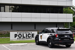 A black-and-white police SUV is parked near a large Pascagoula Police Department sign outside a gray building.