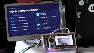 A computer monitor displays information about an Edge AI Deployment Course beside a small electronic device with a built-in screen.