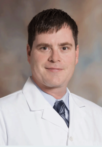 Portrait of Bart Edmiston in a white medical coat and tie.