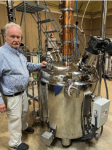 Greg Phillips stands next to a large stainless-steel distilling tank inside Beaver Creek Distillery.