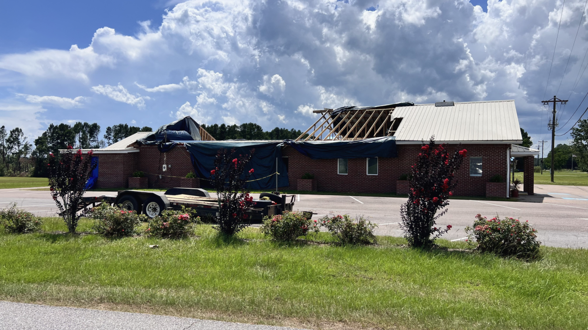 Coaltown Baptist Church with large sections of its roof torn away and covered by blue tarps after tornado damage in the Coal Town community.