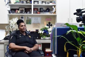 Lumberton Police Chief Elsie Cowart sits in her office with shelves displaying framed certificates, awards and other personal items behind her.