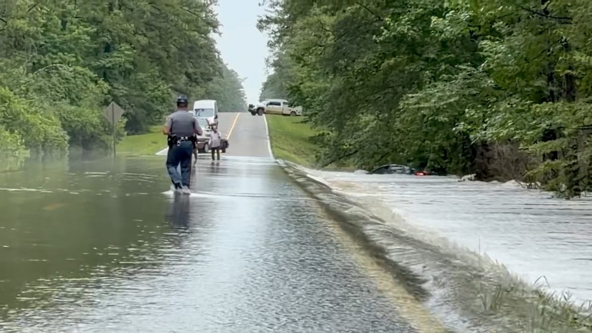 A state trooper walks through floodwater covering Mississippi Highway 26 in Stone County.