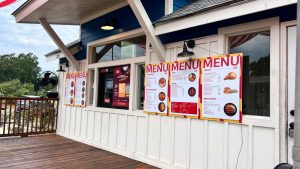 Menu boards mounted outside Jamba Jollof display the restaurant’s food offerings.